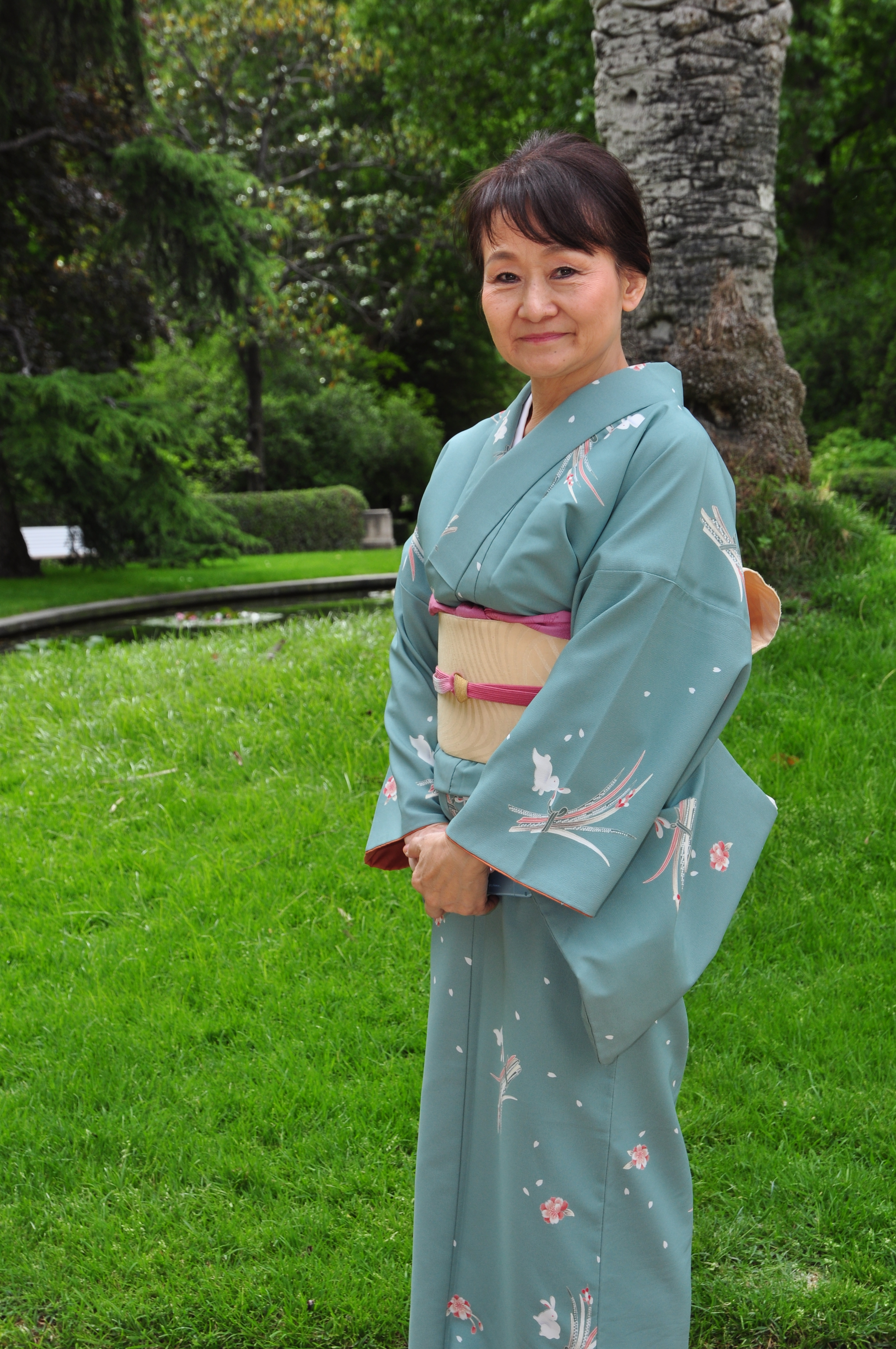 Mujer vestida con un kimono verde, en un parque.