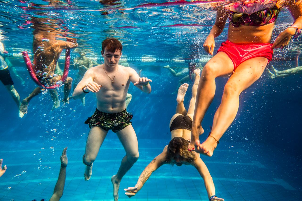 Grupo de jóvenes sumergidos en una piscina.