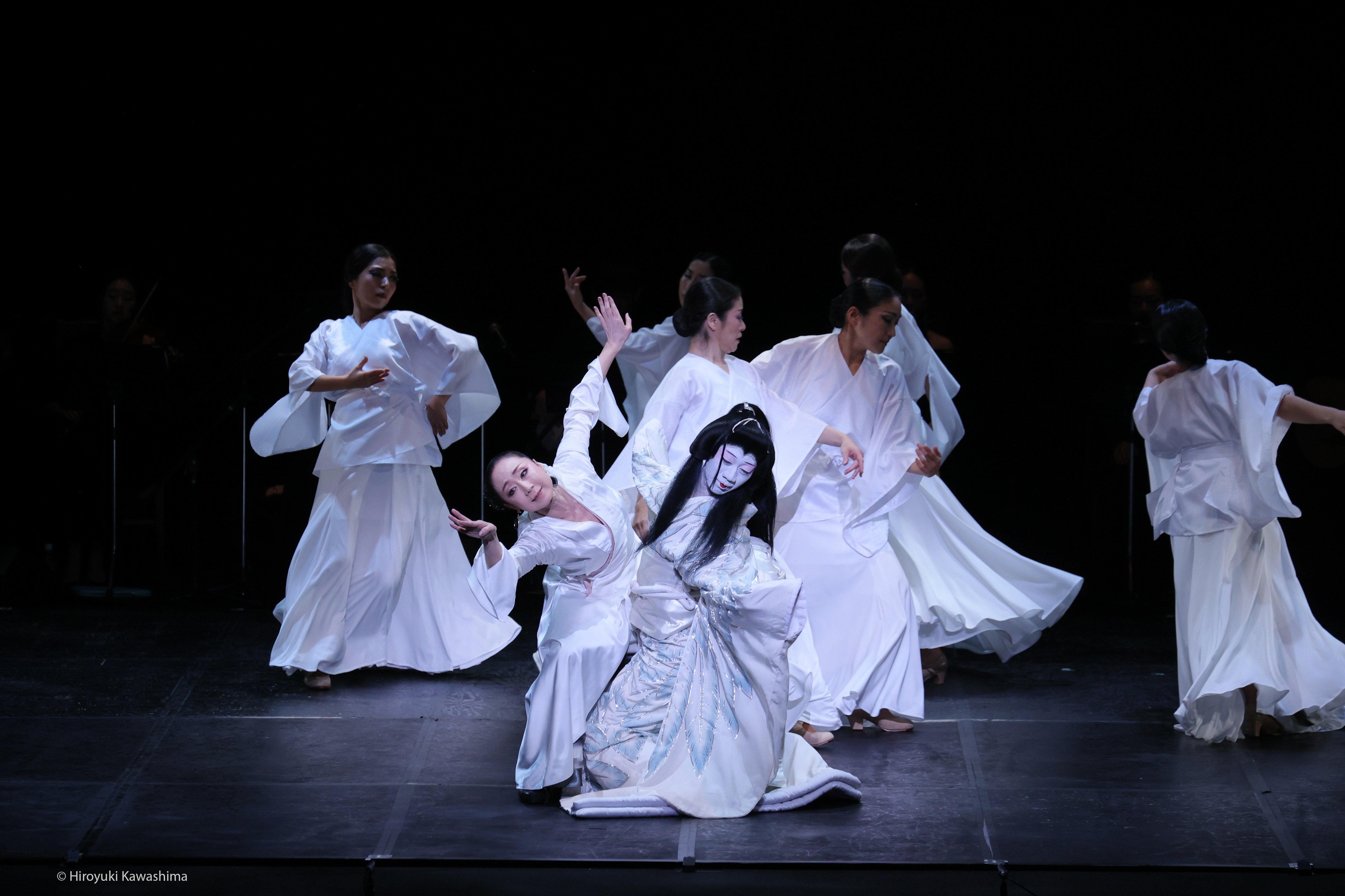 Mujeres japonesas bailando en un escenario.  Todas van vestidas de blanco.